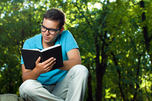 Мужчина в очках читает бумажную книгу