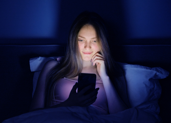 Девушка ночью смотрит в экран смартфона