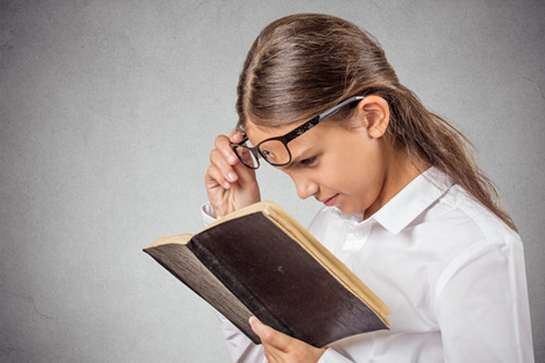 Девочка читает книгу в очках