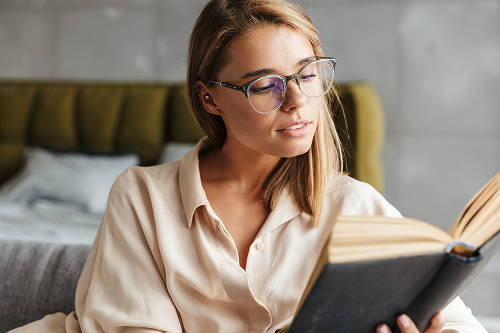Женщина в очках читает книгу